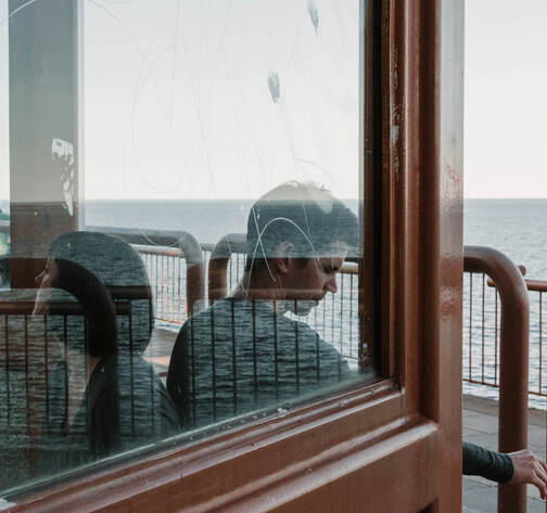 a photography by Kayla Schiltgen of two people sitting under a shelter. Duluth, Minnesota overlooking Lake Superior.